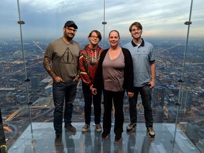 Four family members standing on a glass floor high above Chicago
