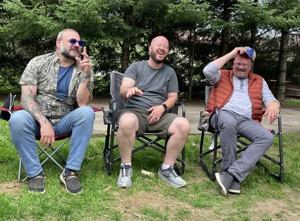 Scott and two friends laughing in camp chairs on the grass