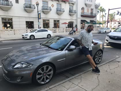 Scott leaning against a gray Jaguar XKR convertible on a street in St. Augustine