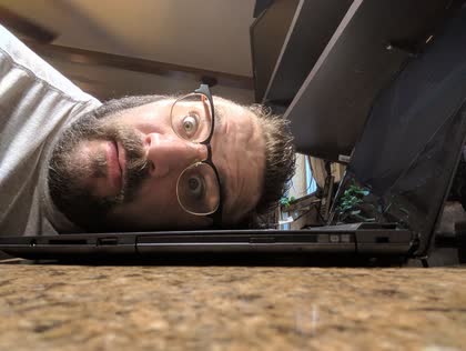 Scott resting his head on a laptop, looking worn out