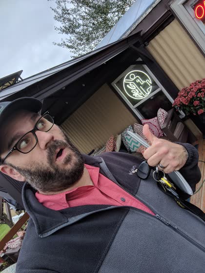 Scott pointing at the new Northwoods Computer Guy sign in front of the shop